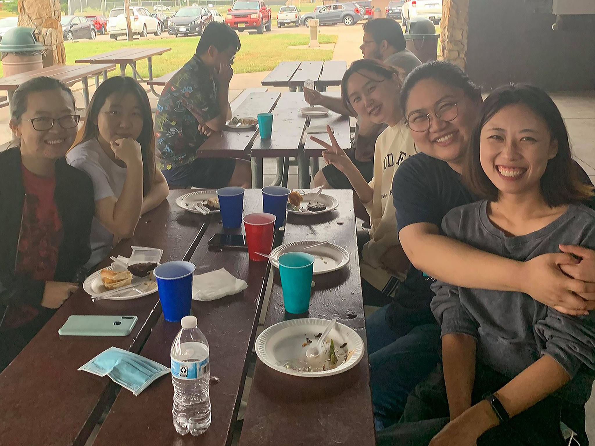 Five students seated around a picnic table smile for camera